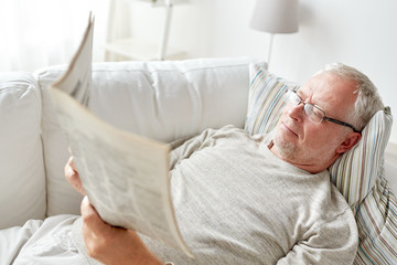 close up of senior man reading newspaper at home