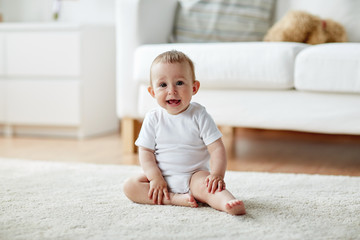 Fototapeta premium happy baby boy or girl sitting on floor at home