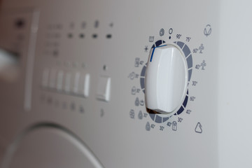front rotate dial knob of white clothes washing machine - selective focus