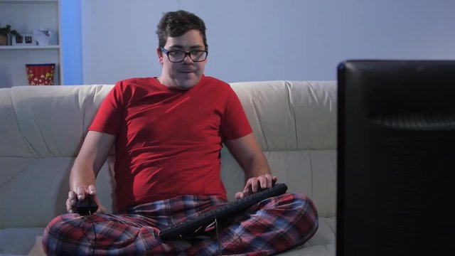 Funny man playing a computer game sitting on big couch