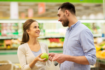 happy couple buying apples at grocery store