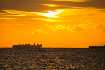 Container ship on the horizon and the pier at sunset