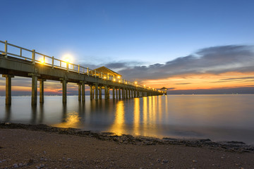 wooden bridge laying into the sea at sunset scenery