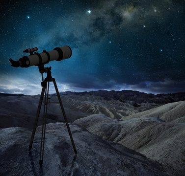 telescope tripod pointing the milky way in a desert landscape