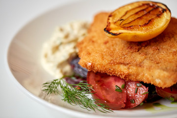 close up of fish salad with roasted lemon on plate