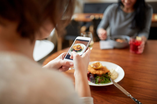 women with smartphones and food at restaurant