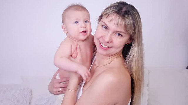 happy mother kissing her son's baby in studio on white background