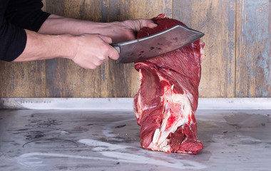 a butcher with an ax chopping meat, beef
