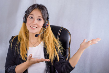 Portrait of happy smiling cheerful young support phone operator in headset showing copy space area...