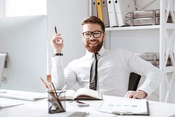 Happy businessman writing notes. Looking at camera.