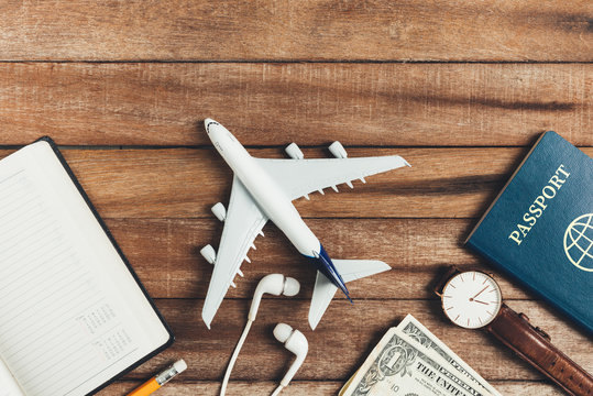 Preparation for Traveling concept, pencil, watch, money, passport, airplane, noted book,  earphone, on a vintage wooden background with copy space.
