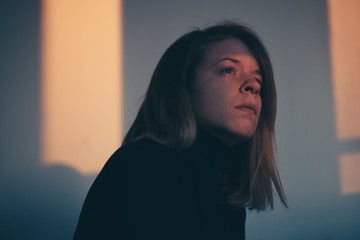 A woman sitting alone and depressed in window light