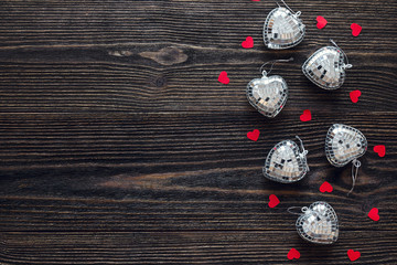 Background with red and glassy hearts on old dark wooden table.