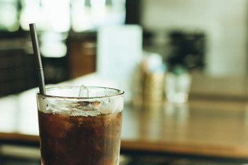 Cold black coffee on the table in the coffee shop with vintage f