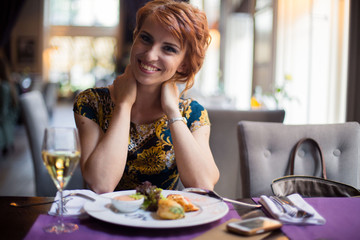Gorgeous young woman drinking red wine alone in restaurant