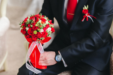 Groom is holding bridal bouquet