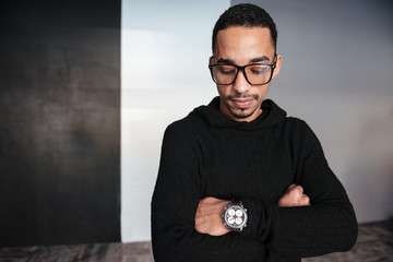 Serious african american young man looking at wristwatch