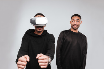 Two joyful african american young men using vr device.