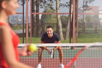 Young adult woman playing tennis against man