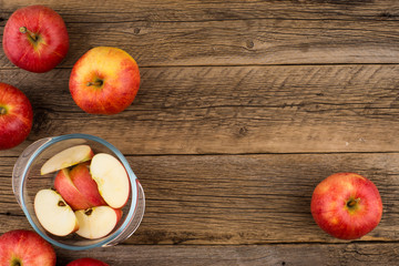 Sliced apples in a glass bowl on the old wooden table.