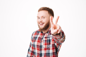 Naklejka premium Smiling Bearded man in shirt showing peace sign