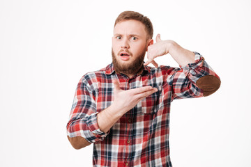 Fototapeta premium Surprised Bearded man in shirt showing phone sign