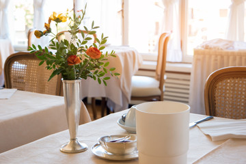 Flowers on dining table. Food establishment interior. Tasty food and quality service.