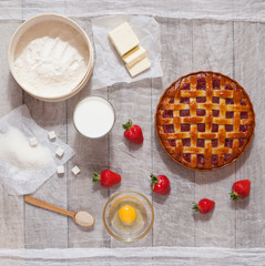 Traditional homemade strawberry pie tart cake sweet baked pastry food with the ingredients of which it is a bright kitchen table. Flat lay.