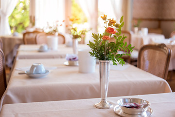 Vase with flowers on table. Blurred restaurant background. Tasty food and fast service.