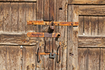 Old brown wooden door with rusty handles and locks