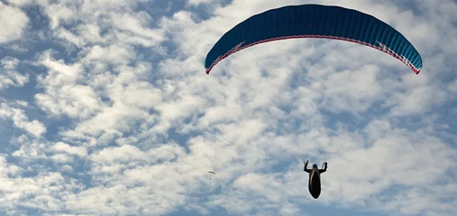 Foto auf Acrylglas Luftsport Gleitschirmflug mit blauem Himmel und einigen Wolken