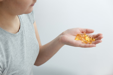 Obraz premium Hand is giving capsules Omega 3 on white background.