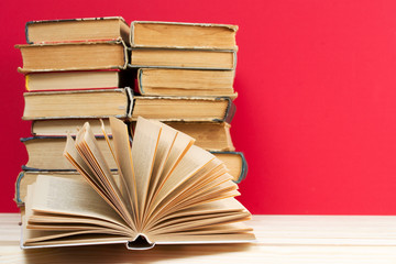 Open book, stack of hardback books on wooden table. Back to school. Copy space