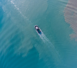 Top view of motion tugboat at azure water with a spot of oil.