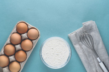 Eggs and ingredients for baking on a light green background. Top