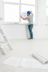 White interior for renovation and repair with ladder, windows and foreman or builder looking at...
