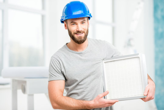Worker holding air filter for installing in the house ventilation system. Purity of the air concept