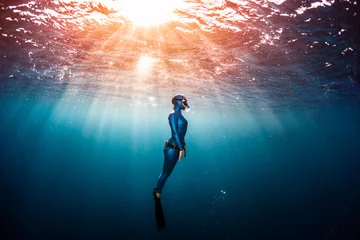 Fotobehang Woman free diver ascending from the depth in a tropical clear sea © Dudarev Mikhail