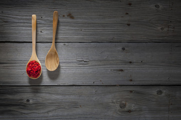 white pepper and goji berries on wooden spoons and wooden background