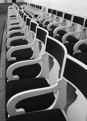 Rows of old chairs in auditorium. Black and white photo