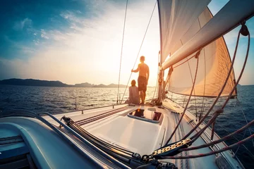 Poster Im Rahmen Paare, die den Sonnenuntergang vom Deck des Segelboots genießen, das sich in einem Meer bewegt © Dudarev Mikhail