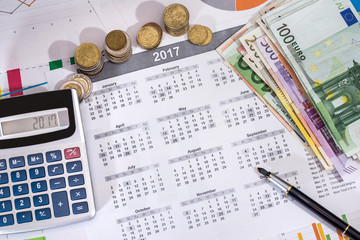 2017 calendar, pen, euros bills and calculator placed on a table.