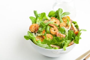 Shrimp salad with cherry tomatoes in bowl on white background with a glass of water. Copy space.