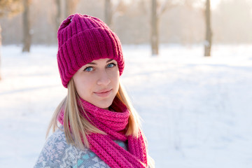 Closeup winter portrait of young girl in pink hat and scarf