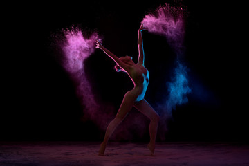 Obraz na płótnie Canvas Slender girl dancing in color powder cloud