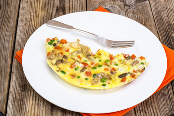 Half an omelette with vegetables on a white plate