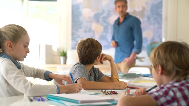 Teacher standing in classroom, kids attending geography lesson