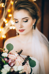 Fototapeta premium Portrait of bride with bouquet in Studio. Background garlands .
