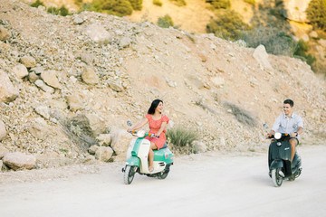 Happy young couple in love on retro motorbike driving togetger and ejoying the trip near the ocean.