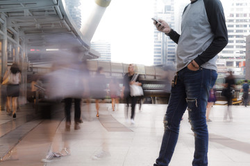 Man holding the phone with People walking in motion blur
